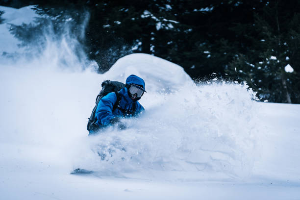 backcountry snowboarder steigt berg ab - telemark skiing stock-fotos und bilder