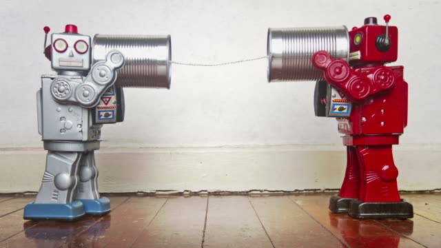 two retro robots on old tin can can phones