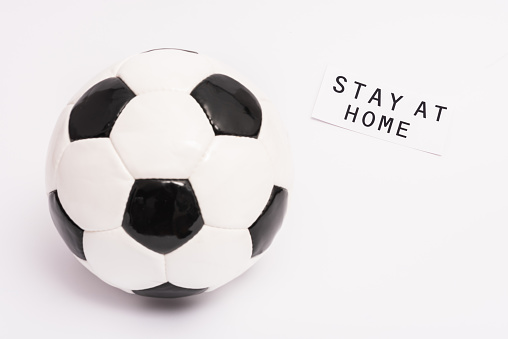 football near paper with stay at home lettering on white with copy space