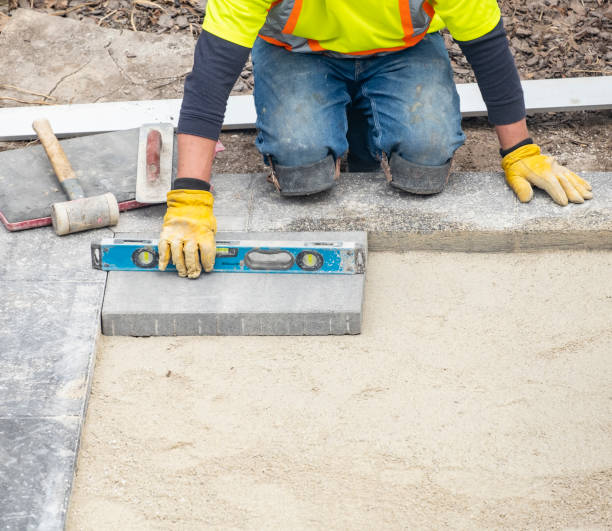 Workman in Safety Jacket Laying Patio Paver Stones