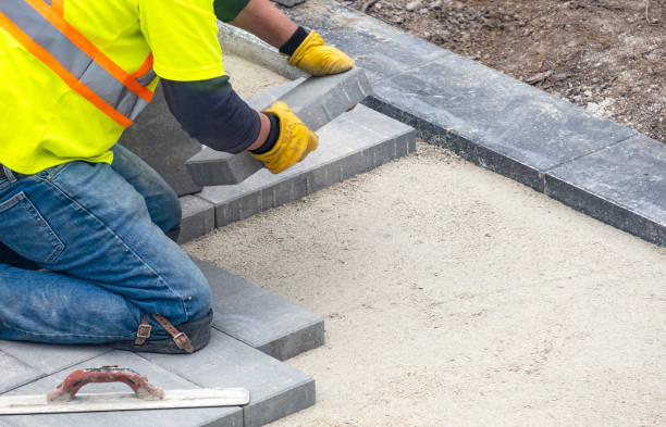 Workman in Safety Jacket Laying Patio Paver Stones
