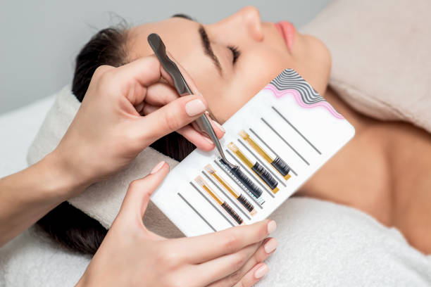 Beautician taking eyelashes by tweezers.
