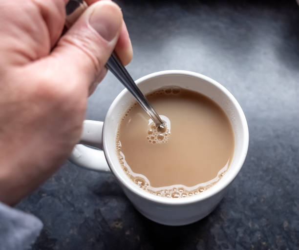 menschliche hand rühren einen becher englischen frühstückstee mit einem teelöffel - rühren stock-fotos und bilder