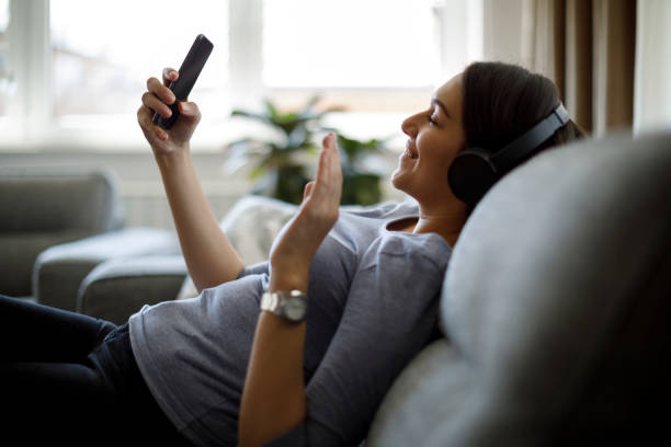 istock Smiling young woman with headphones using mobile phone 1221886552