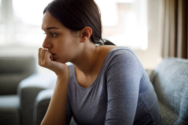 расстроенная женщина, сидящая на диване одна дома - women crying distraught thinking стоковые фото и изображения