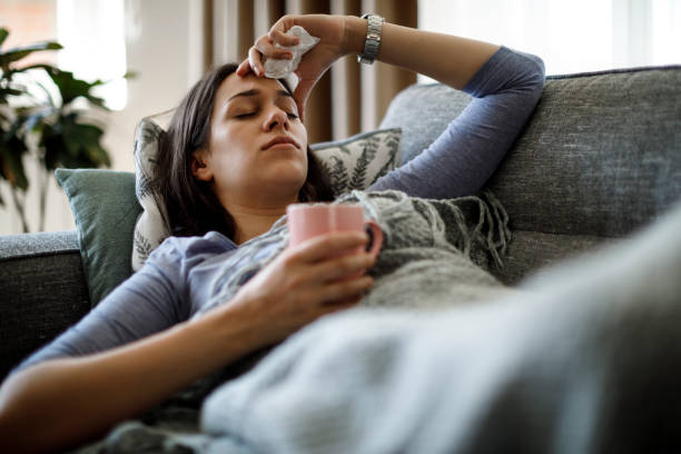 donna malata sdraiata a letto - symptom foto e immagini stock