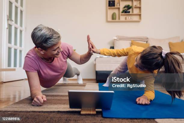 Mother And Daughter Exercising Watching An Online Training Stock Photo - Download Image Now