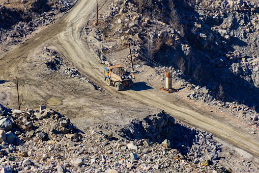 Aerial view of a mining quarry with heavy machinery, surrounded by forest.