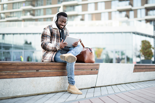 African American man watching content on a digital tablet outdoors.