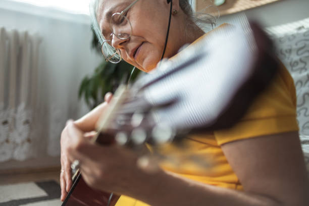 istock Senior woman playing guitar ay home 1221891739