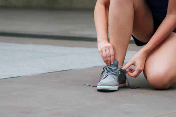 scarpe da ginnastica sportive giovane donna si inginocchiò fare su lacci da scarpe. scarpe da corsa pronte in palestra sportiva persona di jogging. le mani ravvicinate legano i lacci delle scarpe runner nello stile di vita sano della palestra fitness. - lying down moving down pilates yoga foto e immagini stock