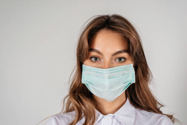istock Young long-haired woman in protective medical mask over white background 1221892811