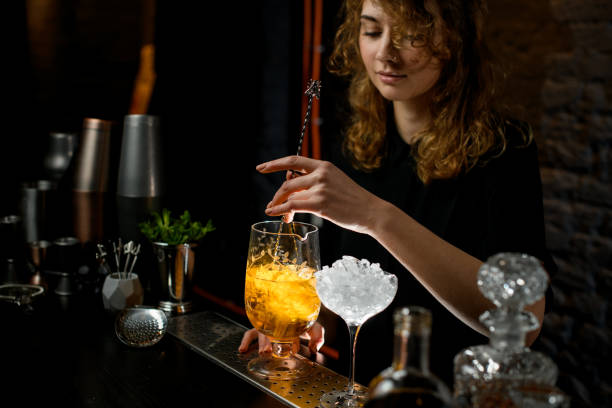 istock Young bartender mixed cocktail in large glass with bar spoon. 1221892971