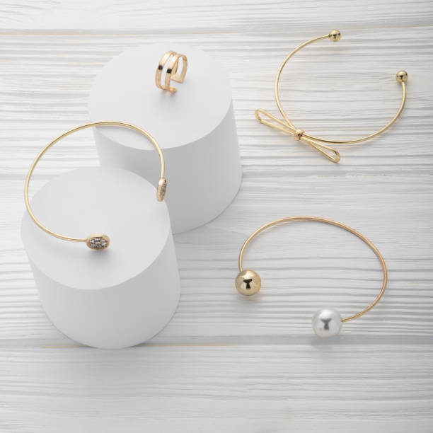 istock Collection of three bracelets and ring on white platforms on wooden background with copy space 1221893913