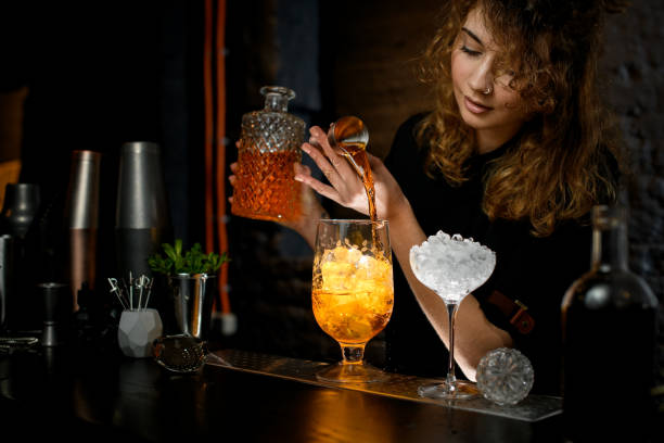 istock Female bartender carefully pours drink from jigger into glass. 1221894921