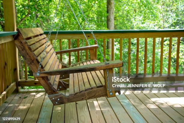 An Old Wooden Bench Swing On A Newly Built Porch Stock Photo - Download Image Now - Deck, Swing - Play Equipment, Wood - Material