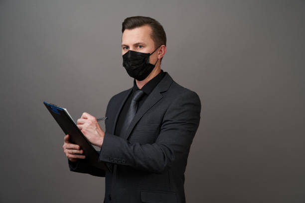istock Businessman with surgical medical mask Holding a Clipboard document 1221897212
