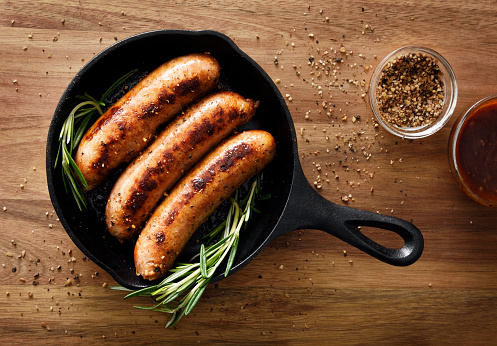 Three sausages in a cast iron skillet with seasoning