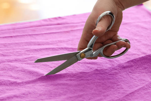 istock Close-up of male hand using scissor tip on purple fabric 1221897521