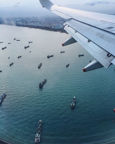 View from aircraft window of cargo ships at the sea outside Singapore harbour