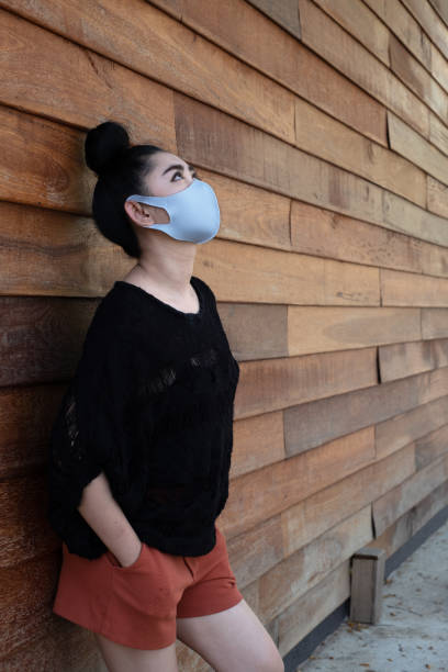 feche a jovem asiática colocando uma máscara médica - wind textile women retro revival - fotografias e filmes do acervo