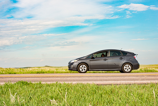 By Rapid City, United States a Toyota Prius on a cross country road trip parks by the side of the road in Badlands National Park South Dakota.