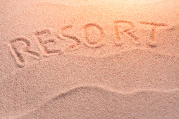 istock RESORT lettering on sand with wave and evening light. Minimal exotic vacation and travel concept, Flat lay top view copy space 1221900579
