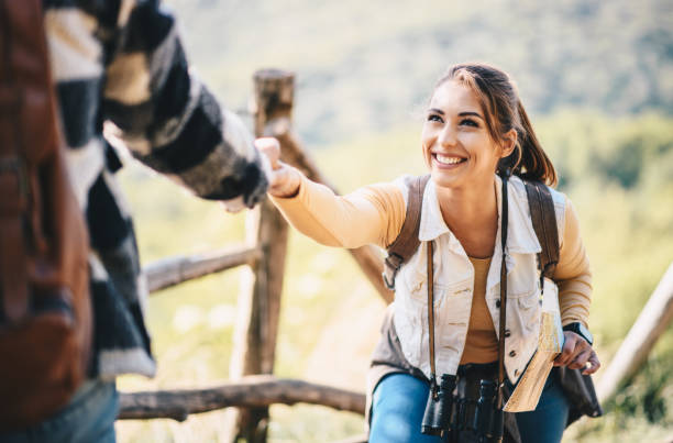 istock Man helping a woman out to climb on a hill. 1221903626