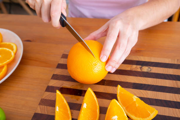 istock Female hands holding knife and cutting orange 1221906376