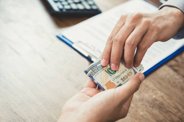 istock Businessman giving money, US dollars, to his partner while making contract 1221913967