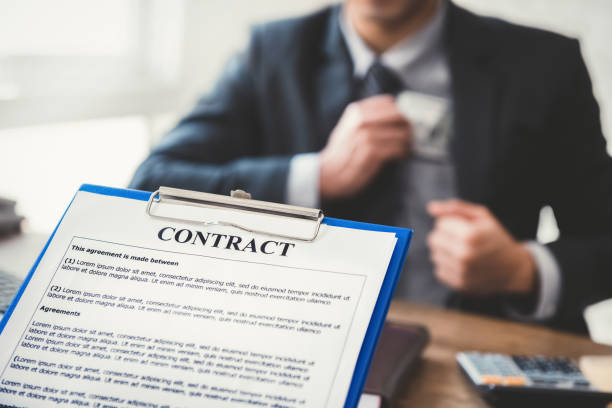 istock Businessman keeping money into his suit pocket while making contract 1221914032