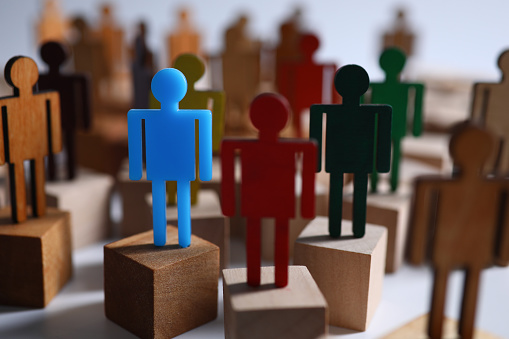 Close-up of colourful plastic figures standing on wooden blocks. Symbol of leadership and uniqueness. Business and success in career. Strategy and goal planning concept