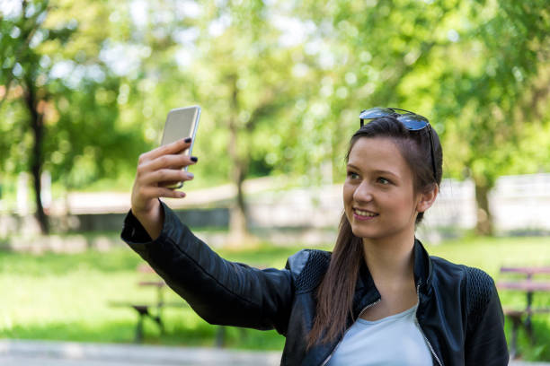 istock A woman uses a phone in a park 1221914627