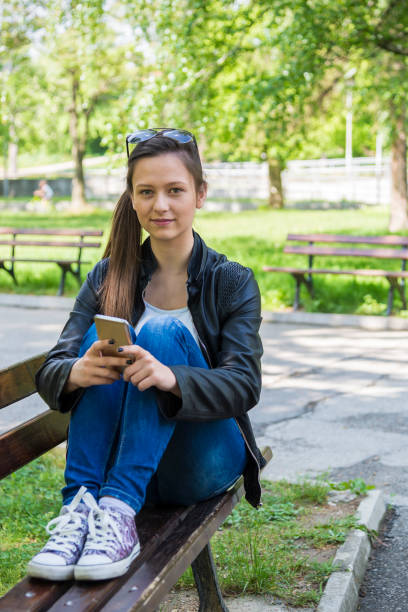 istock A woman uses a phone in a park 1221914637