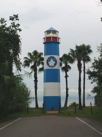 A blue and white lighthouse surrounded by palm trees on the coast of the Gulf of Mexico in Kemah, Texas, USA, not far from Houston.