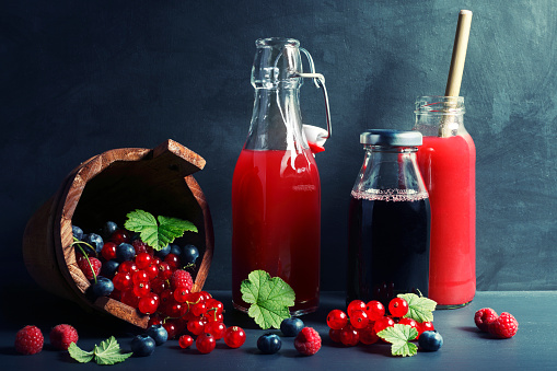 Glass bottles of various fruit juices and smoothies  with fresh berry fruits.