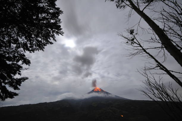 Tungurahua volcano, ecuador Tungurahua,  5,023 meters (16,480 ft) is located in the Cordillera Oriental of the Andes of central Ecuador according to one theory the name Tungurahua is a combination of the Quichua tunguri (throat) and rahua (fire) meaning "Throat of Fire". According to another theory it is based on the Quichua uraua for crater.  Tungurahua is also known as "The Black Giant" and, in local indigenous mythology it is allegedly referred to as Mama Tungurahua ("Mother Tungurahua"). mt tungurahua sunset mountain volcano stock pictures, royalty-free photos & images