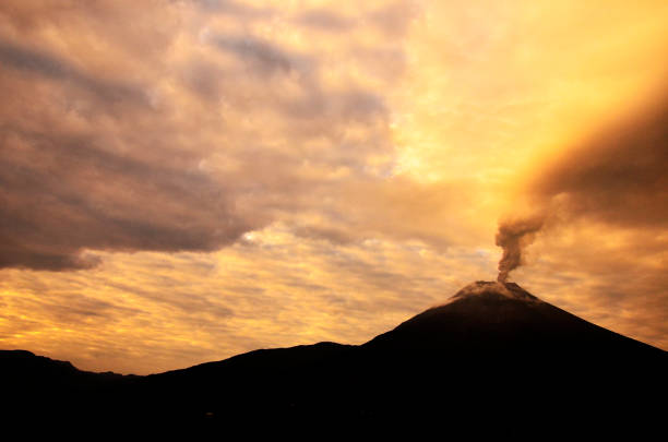 Tungurahua volcano, ecuador Tungurahua,  5,023 meters (16,480 ft) is located in the Cordillera Oriental of the Andes of central Ecuador according to one theory the name Tungurahua is a combination of the Quichua tunguri (throat) and rahua (fire) meaning "Throat of Fire". According to another theory it is based on the Quichua uraua for crater.  Tungurahua is also known as "The Black Giant" and, in local indigenous mythology it is allegedly referred to as Mama Tungurahua ("Mother Tungurahua"). mt tungurahua sunset mountain volcano stock pictures, royalty-free photos & images