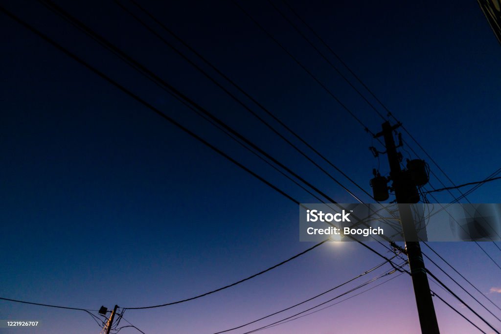 Dark Miami Wynwood Night Sky with Silhouette of Telephone Pole with Wires In Miami, USA as the dusk darkens into night a telephone pole with cable wires is silhouetted  against the sky. Telephone Pole Stock Photo