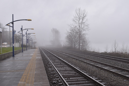 Dusk view of outdoor train station. Foggy and misty. No people.