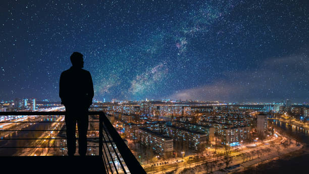 o homem em pé no topo da construção no fundo da paisagem da cidade estrelada - boa noite - fotografias e filmes do acervo