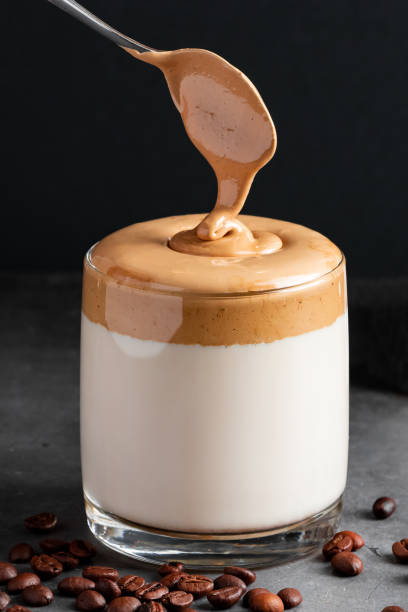 istock Dalgona coffee on a black background. The process of making a trendy drink. Fluffy sweet foam in a glass with iced milk. 1221928837