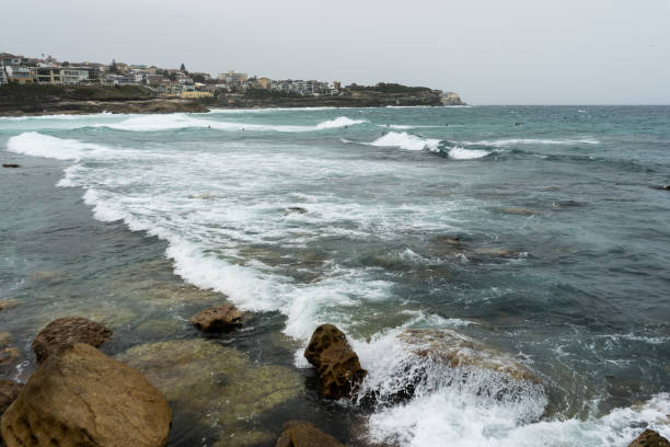 istock Waves breaking on to rocks with city in the background 1221931175