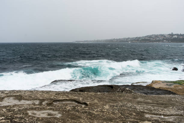 Photo of waves crashing onto rocks on an overcast day
