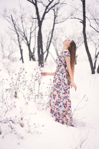 Smiling young woman outdoors on the snow wearing a sundress.
