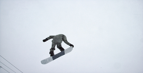 A Snowboarder in Full Winter Gear Attempting a 