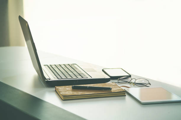 istock work from home, a glasses above laptop computer on a white modern business office desk table with a notebook and tablet with blank workspace for text input, interior design in calm concept 1221945457