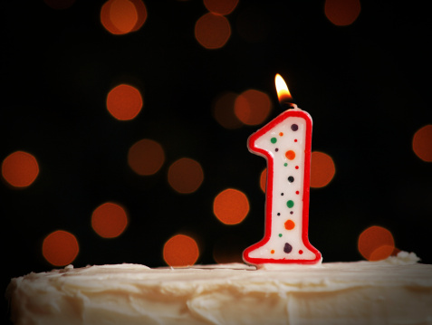 a first birthday candle cake on a defocused background.