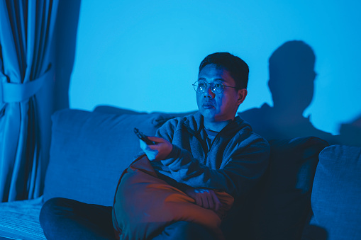 an asian chinese mid adult watching movies at home alone at night in darkness