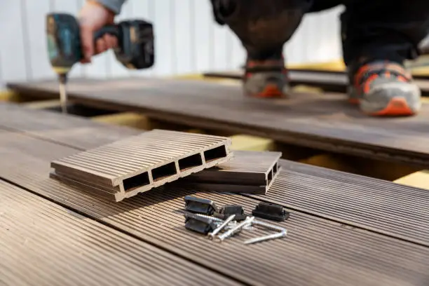 Photo of wpc terrace construction - worker installing wood plastic composite decking boards